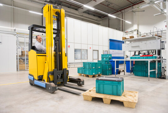 Man on forklift in a factory transporting box