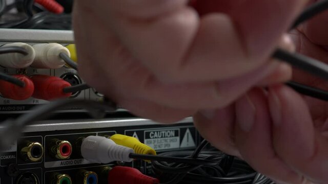 Male Hands Connecting Cables To A DVD Player. Close-Up. Component Video Cables Plug-In To Multimedia Electronic Device At Home..