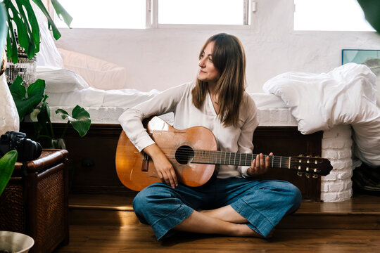 Smiling Woman Playing Guitar At Home