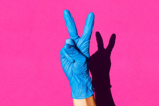 Hand Of Woman Wearing Latex Glove Making V Sign