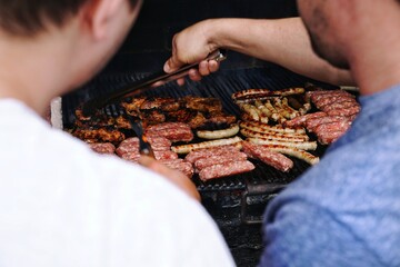 Men preparing meat on grill