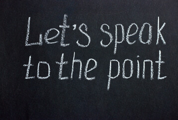 
Lettering on a dark board "Let's speak to the point". The expression is often used in business and education