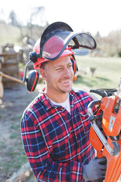 Thoughtful lumberjack holding chainsaw during sunny day