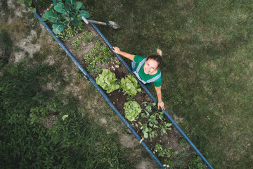 Drone shot of smiling woman standing by raised bed in yard