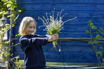 Portrait of a girl in allotment garden holding bunch of flowers