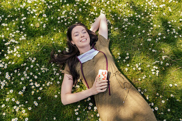 Woman with let down face mask enjoying her free time while lying on grass with daisies