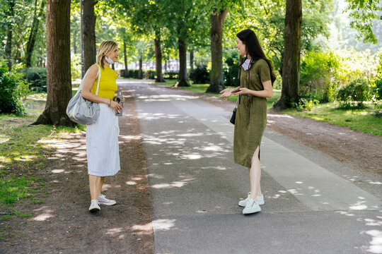 Two women meeting in nature with let down face masks