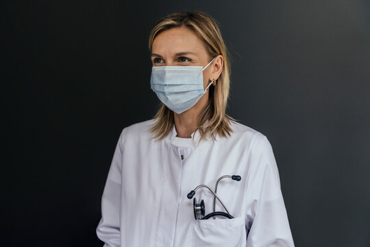 Portrait of doctor wearing protective mask against grey background