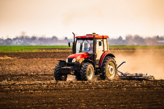 Fototapeta Farmer in tractor plowing farm against sky