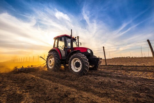 Man in tractor plowing agricultural land against cloudy sky