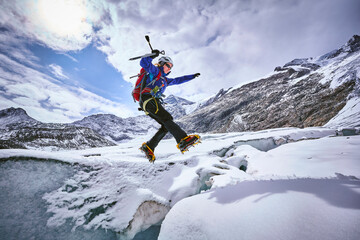 Female mountaineer jumping over crevasse, Glacier Grossvendediger, Tyrol, Austria