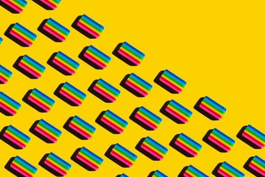 Pattern of rainbow colored erasers against yellow background