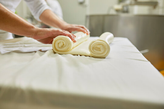 Cheese production, female worker rolling cheese, rolled layered cheese