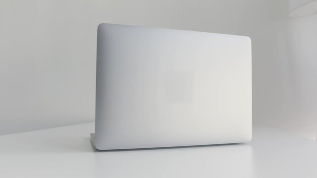 Rear view of a white laptop isolated on white background. Action. Modern slim design of a new laptop made of aluminum material on white table, concept of modern technologies.