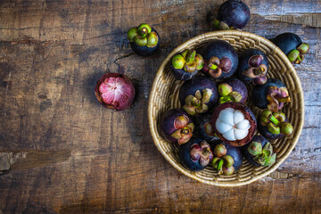 Fresh mangosteen fruit in a basket on the wooden table, Top view