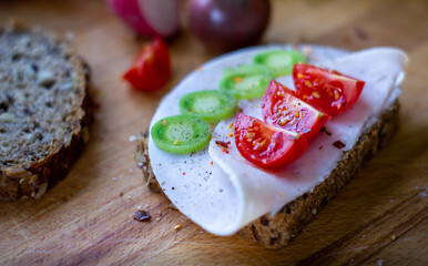 Brot und Brotscheiben liebevoll garniert mit Schinken, Tomaten Lauch und Chilliflocken