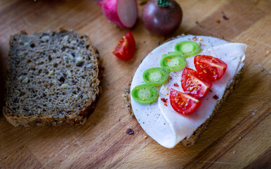 Brot und Brotscheiben liebevoll garniert mit Schinken, Tomaten Lauch und Chilliflocken