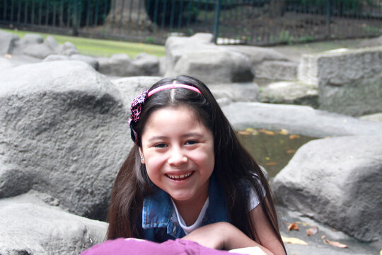 Latin Women, Mother And 8 Year Old Girl Sitting On Gray Rocks