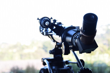 Close up of a telescope pointing out a window during day time
