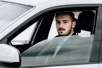 Man looking outside his cars window sitting in the front seat