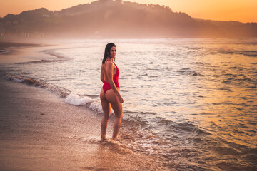 Young caucassian girl possing with a red bikini in the beach.