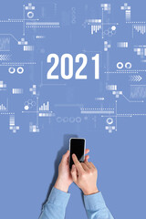 A man holds a smartphone with the inscription 2021. top view and blue background.