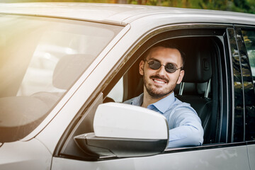 handsome looking man wearing sunglasses while sitting in front of the steering wheel