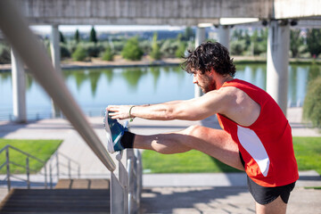 young man in the park practicing stretching to avoid running injuries
