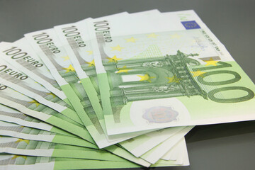 Stack of various one hundred euro bills, one hundred euro cash bills on dark background.