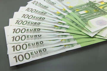 Stack of various one hundred euro bills, one hundred euro cash bills on dark background.