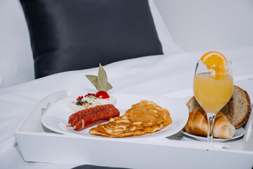 appetizing combination of sausages and an omelette with a glass of orange juice and bread served on a table