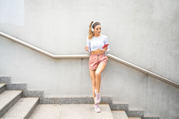 Fit runner girl listening music on the city street.