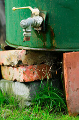 A tap, a water valve in an old metal green barrel.
Garden water installation, self-made from recycled installation elements