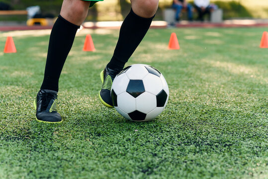 Detail soccer player kicking ball on field. Soccer players on training session. Detail soccer background. Close up of legs and feet of footballer on green grass