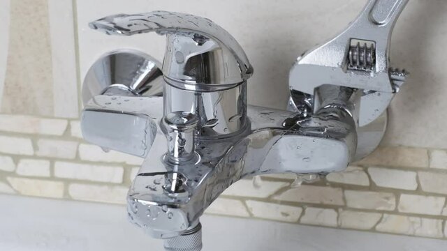 Plumber Fixing a water leaking tap Faucet by Adjustable wrench