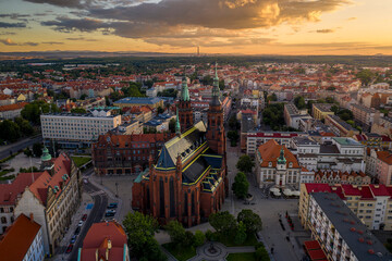 Aerial drone view of the old town buildings and Cathedral of St. Peter and Paul the Apostles at sunset. Giant mountains can be seen in the distance. Old architecture in sun rays in Legnica, Poland
