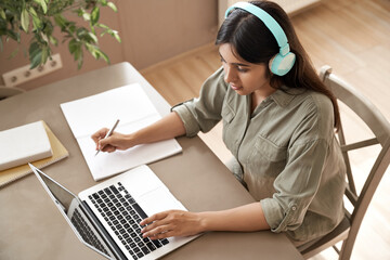 Indian girl student wear headphones learning online watching webinar class looking at laptop...
