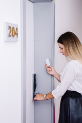 Fototapeta na wymiar woman standing in front of a white door and is about to open it with her keycard in a hotel