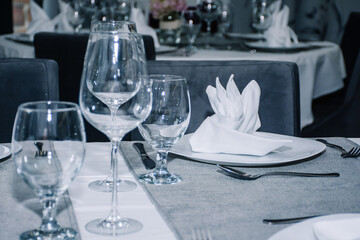 table decorated with cutlery and  glasses for dinner inside a beautiful restaurant