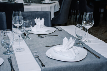 a table for two decorated with glasses for wine, cutlery and dishes with napkins