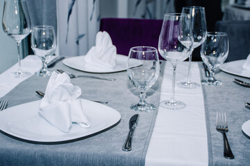 a table for two decorated with glasses for wine, cutlery and dishes with napkins