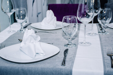 a table for two decorated with glasses for wine, cutlery and dishes with napkins