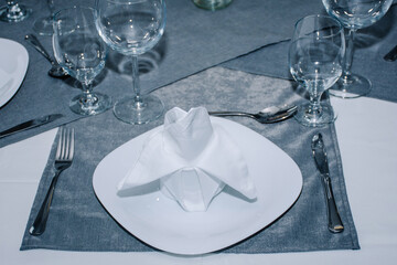 dishes with napkins on top of them, cutlery and glasses nicely decorated around them