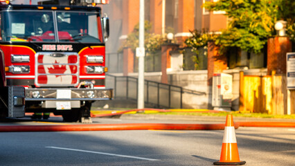 Detour. Bright orange traffic cones standing in a row on dark asphalt with blurred out firetruck at...