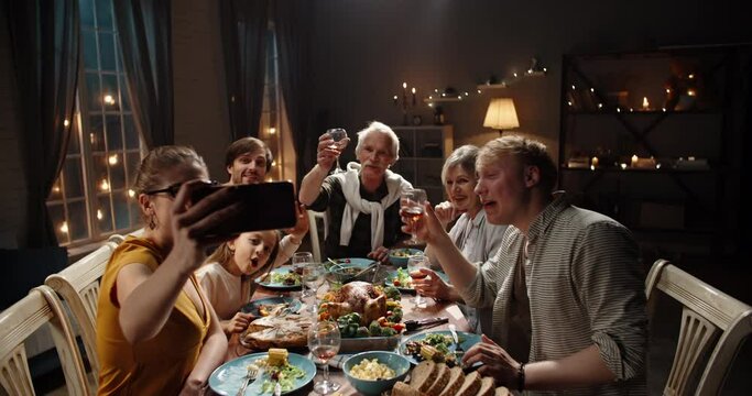 Happy large caucasian family celebrating christmas together at dinner party table, having video chat on smartphone with distant relatives or friends, smiling - holiday, communnication 4k footage