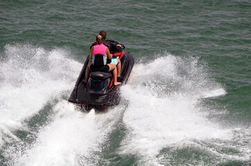 Young couple riding tandem on aa speeding jet ski.
