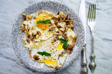 Fried eggs with mushrooms on the stone plate.