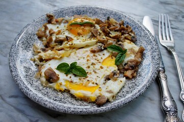 Fried eggs with mushrooms on the stone plate.