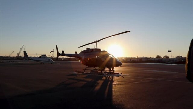Helicopter parked at a hanger with sunlight behind.