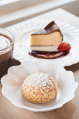 Choux cream, basque cheesecake and hot chocolate on a table